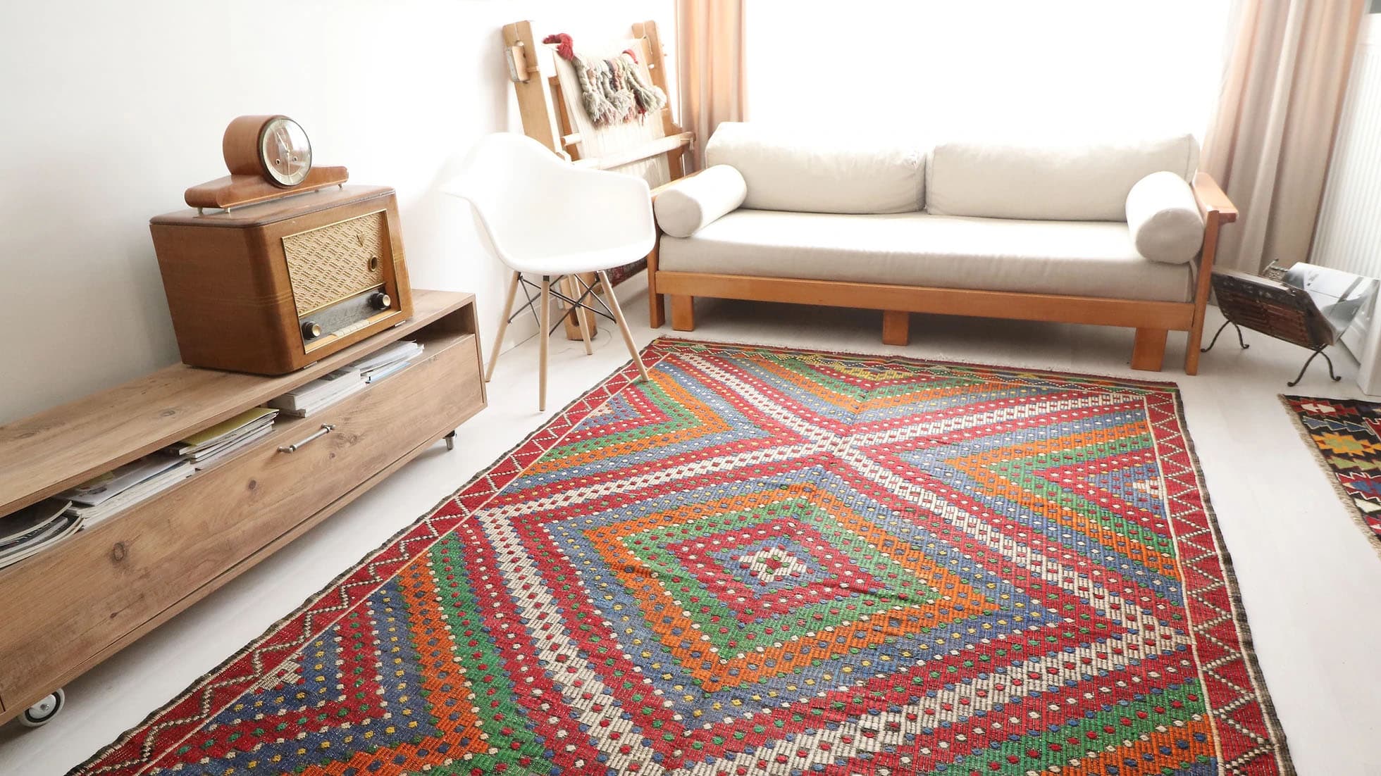 Sunlit living room featuring a vintage Turkish sumac kilim rug, complemented by mid-century modern furniture and natural decor, embodying soulful and sustainable interior design