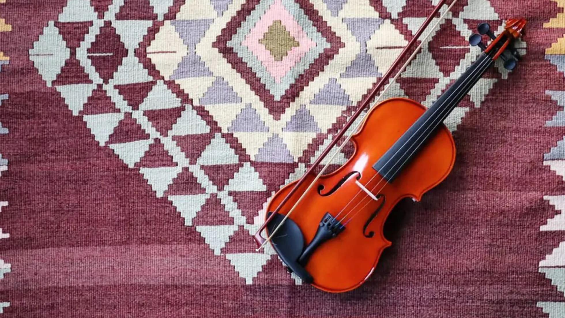 a violin standing on a luxury vintage handwoven Turkish tribal kilim rug