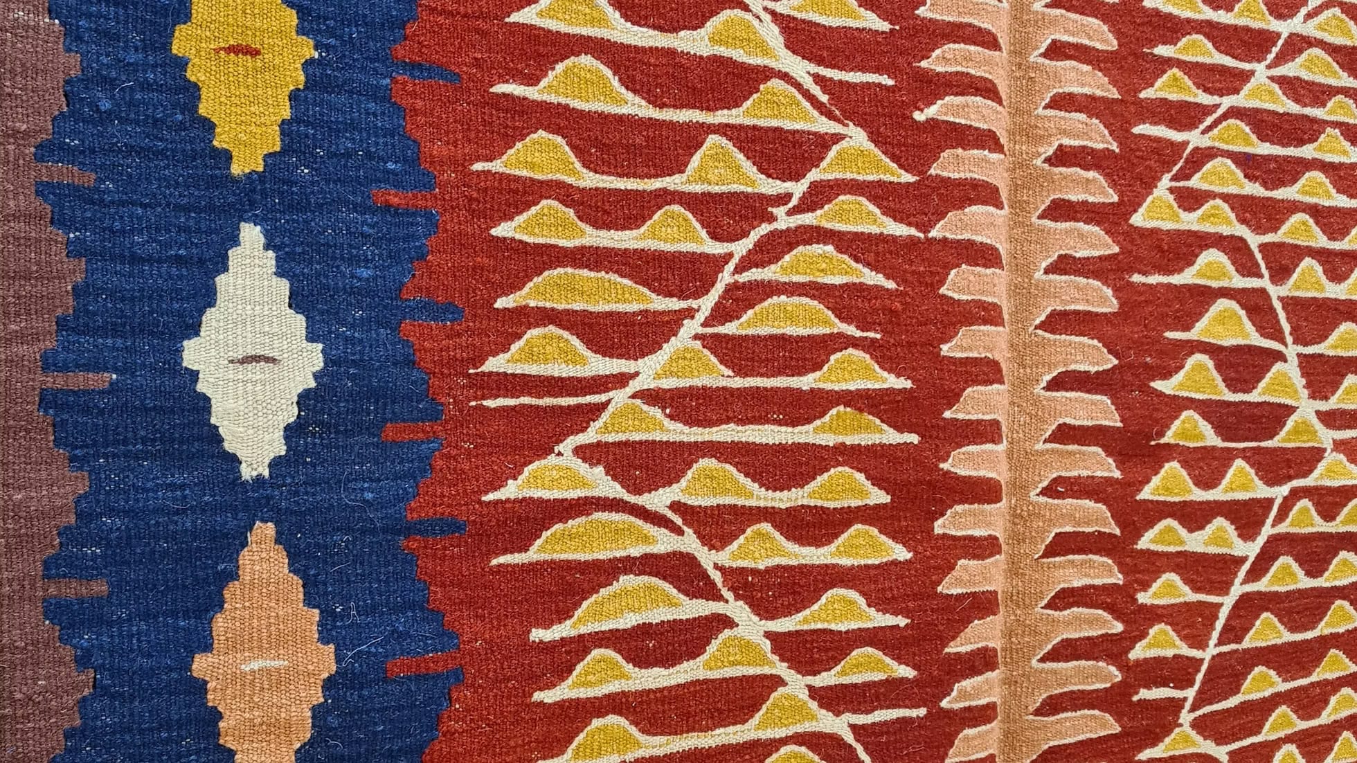 Turkish textile kilim with geometric patterns in blue, red, and yellow.