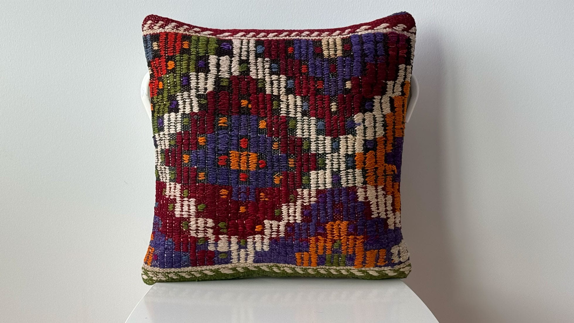High-end vintage handwoven kilim pillow with intricate geometric patterns in deep purple, ivory, and scarlet. Unique, authentic Turkish kilim décor for designers and collectors seeking luxury home accents. Perfect for NYC-based projects and interiors needing a bold, artisanal touch.