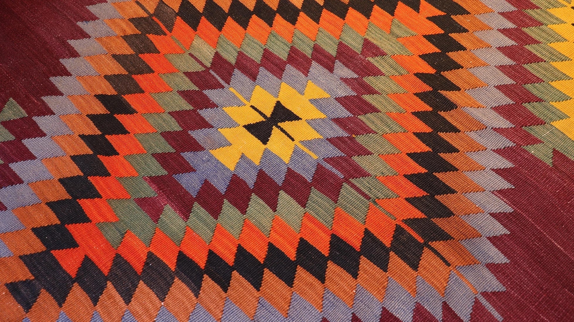 zoom in on the traditional lozenge motif in green, yellow, black, and orange of the vintage runner rug by Kilim Couture New York
