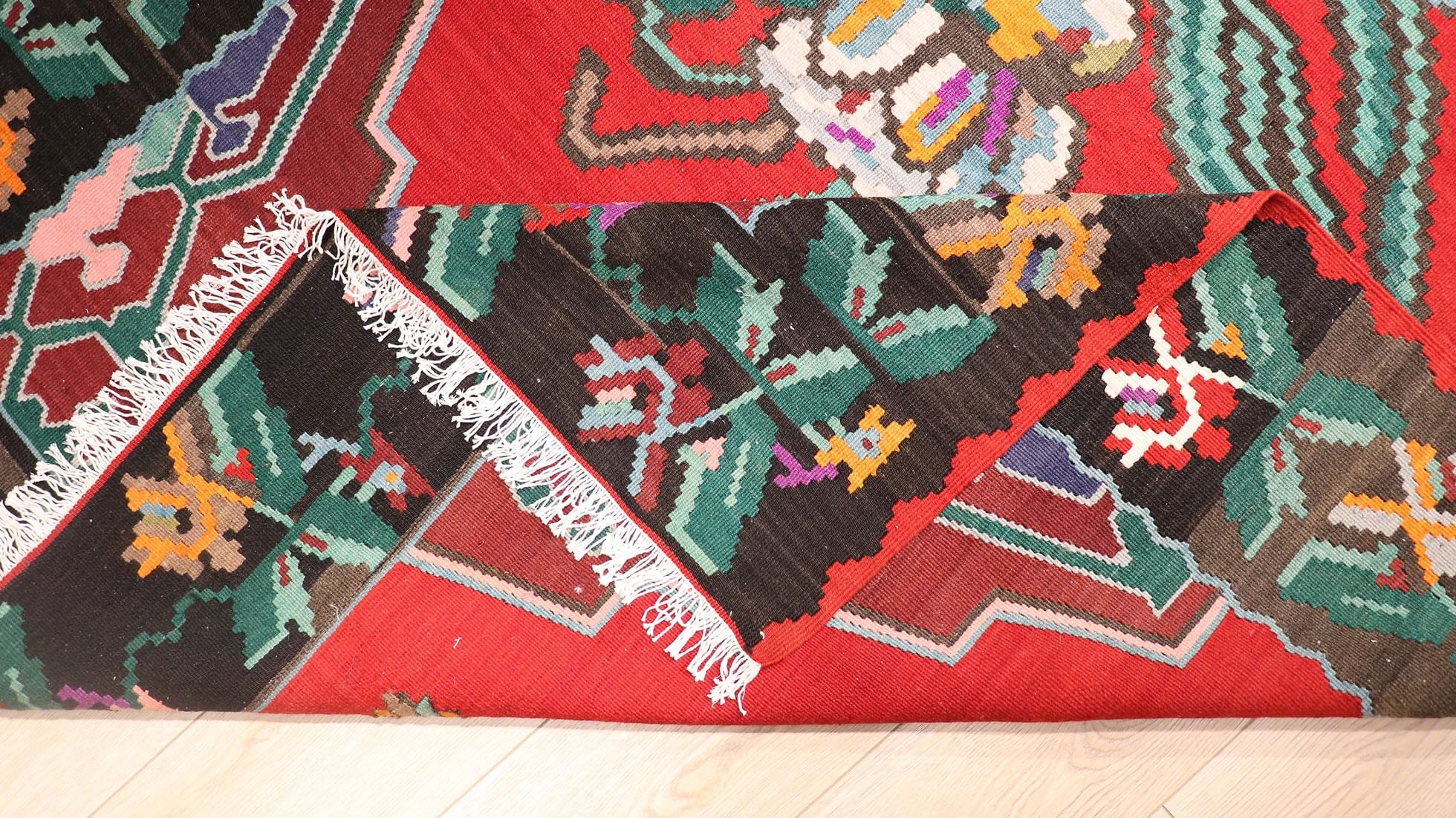 Handwoven vintage Bessarabian kilim rug, 5x7 ft, with a bold oriental red backdrop featuring intricate floral bouquets in cream, aqua green, purple, and lush green foliage, framed by a faded black border with floral accents, showcasing mid-20th century craftsmanship and European elegance.