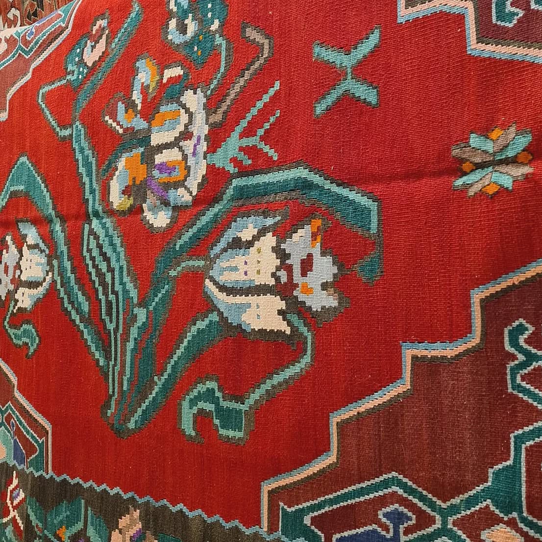 Handwoven vintage Bessarabian kilim rug, 5x7 ft, with a bold oriental red backdrop featuring intricate floral bouquets in cream, aqua green, purple, and lush green foliage, framed by a faded black border with floral accents, showcasing mid-20th century craftsmanship and European elegance.