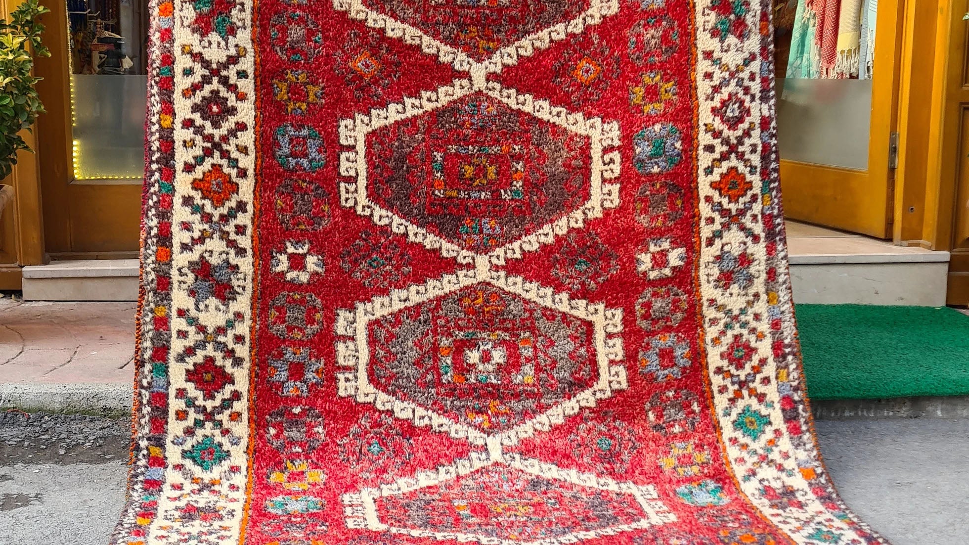 Discover the artistry of the 1970s with this Caucasian hand-knotted rug, a 5x8 ft masterpiece curated by Kilim Couture New York. Featuring a vivid crimson red base and five ivory-edged hexagonal medallions, it showcases intricate geometric and floral motifs. The striking design is framed by an ivory border adorned with vibrant hues of cobalt blue, emerald green, golden yellow, and orange, creating a balanced and versatile aesthetic.