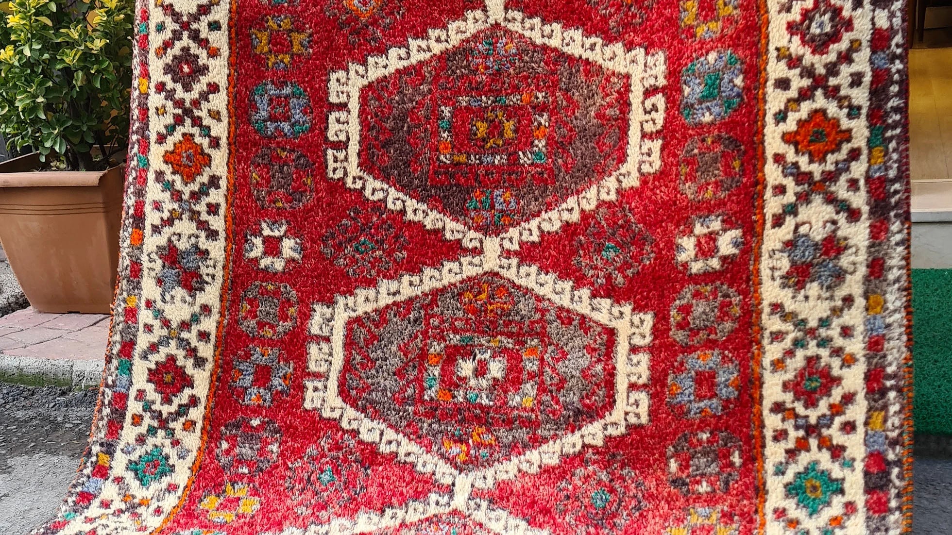 Discover the artistry of the 1970s with this Caucasian hand-knotted rug, a 5x8 ft masterpiece curated by Kilim Couture New York. Featuring a vivid crimson red base and five ivory-edged hexagonal medallions, it showcases intricate geometric and floral motifs. The striking design is framed by an ivory border adorned with vibrant hues of cobalt blue, emerald green, golden yellow, and orange, creating a balanced and versatile aesthetic.