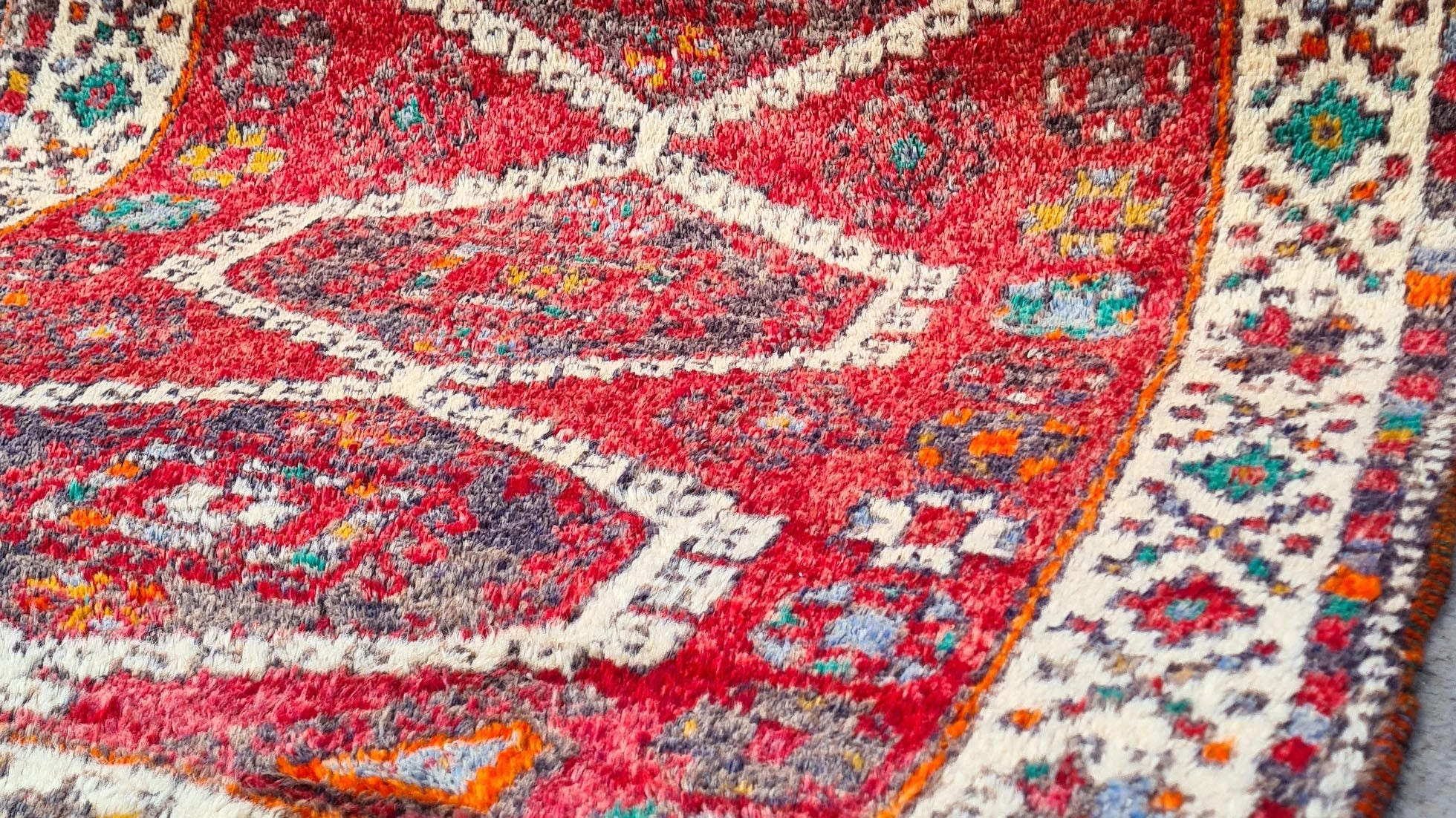 Discover the artistry of the 1970s with this Caucasian hand-knotted rug, a 5x8 ft masterpiece curated by Kilim Couture New York. Featuring a vivid crimson red base and five ivory-edged hexagonal medallions, it showcases intricate geometric and floral motifs. The striking design is framed by an ivory border adorned with vibrant hues of cobalt blue, emerald green, golden yellow, and orange, creating a balanced and versatile aesthetic.