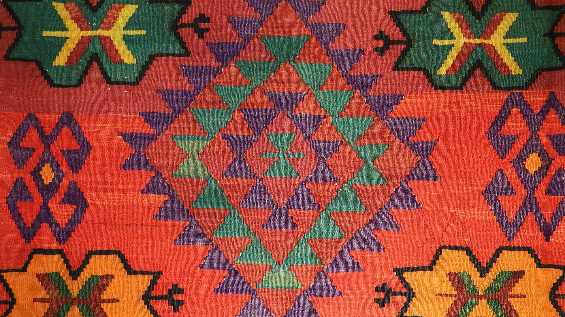 lozenge pattern on a red Caucasian oriental rug in green and purple