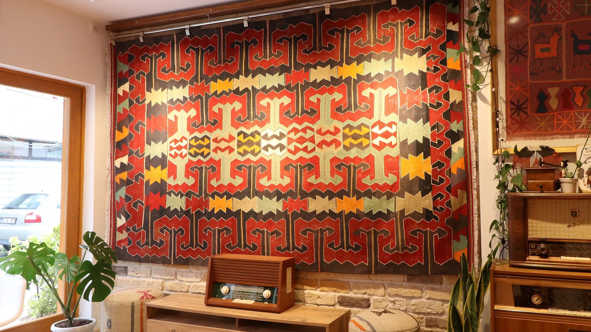 eclectic Anatolian rug showcasing gorgeous traditional motifs in bold terracotta and black colors hung on the wall as a Turkish tapestry rug