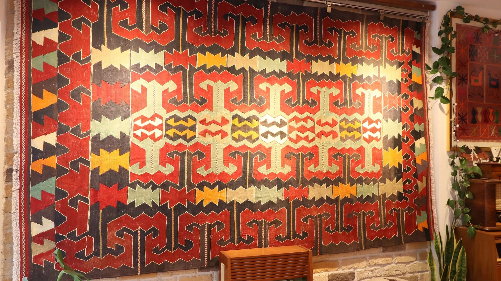 eclectic Anatolian rug showcasing gorgeous traditional motifs in bold terracotta and black colors hung on the wall as a Turkish tapestry rug