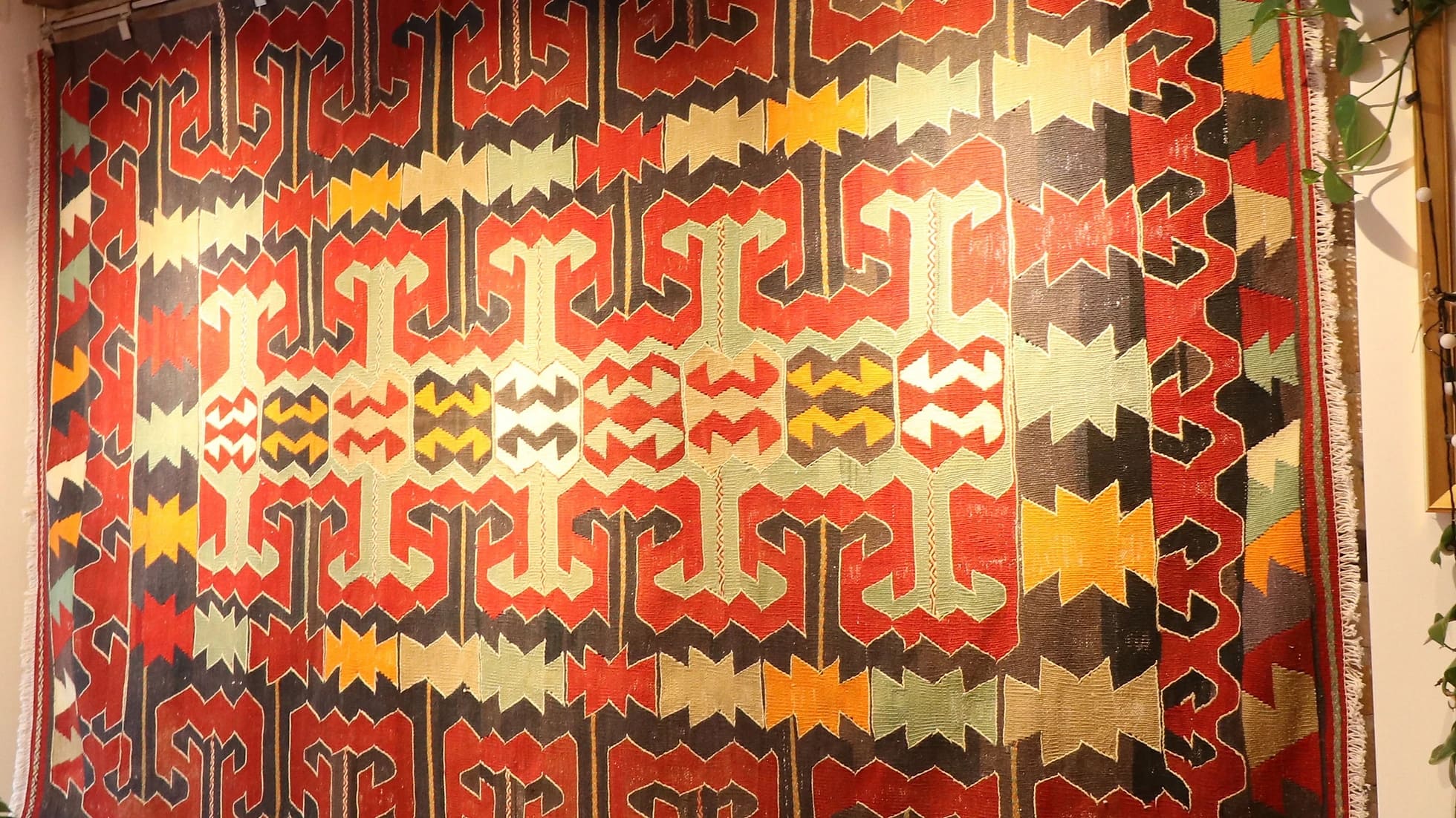 eclectic Anatolian rug showcasing gorgeous traditional motifs in bold terracotta and black colors hung on the wall as a Turkish tapestry rug