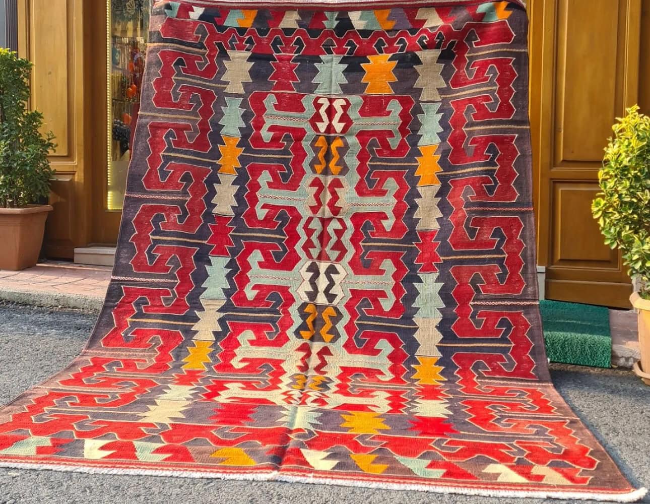 eclectic Anatolian rug showcasing gorgeous traditional motifs in bold terracotta and black colors hung on the wall as a Turkish tapestry rug