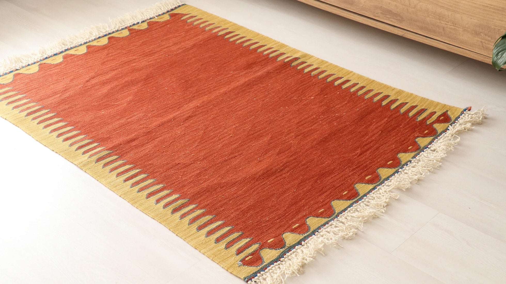 simple and minimal Turkish rug in red and yellow showcasing traditional motifs and white tassels/fringes sourced from the world-renowned city Bodrum