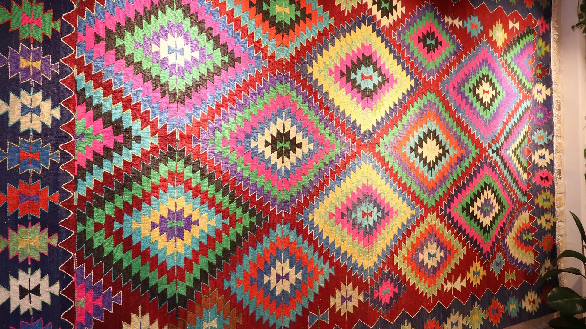 a magnificent and colorful large vintage rug from turkey in traditional motifs and modern style hanging on the wall like a quilt or tapestry