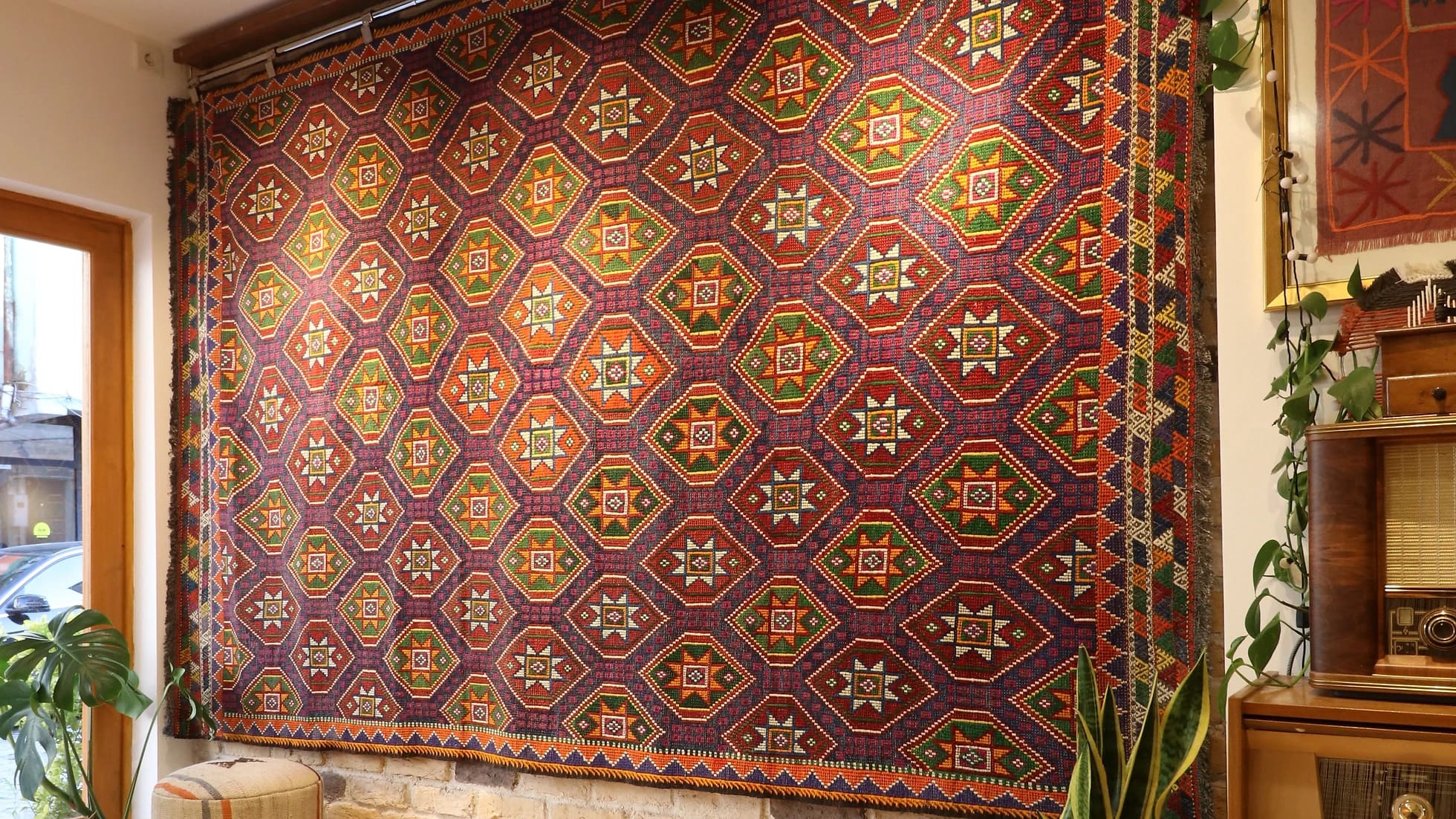 a gorgeous handwoven Turkish flat-woven tribal rug in muted and faded colors hanging on the wall as a Turkish tapestry