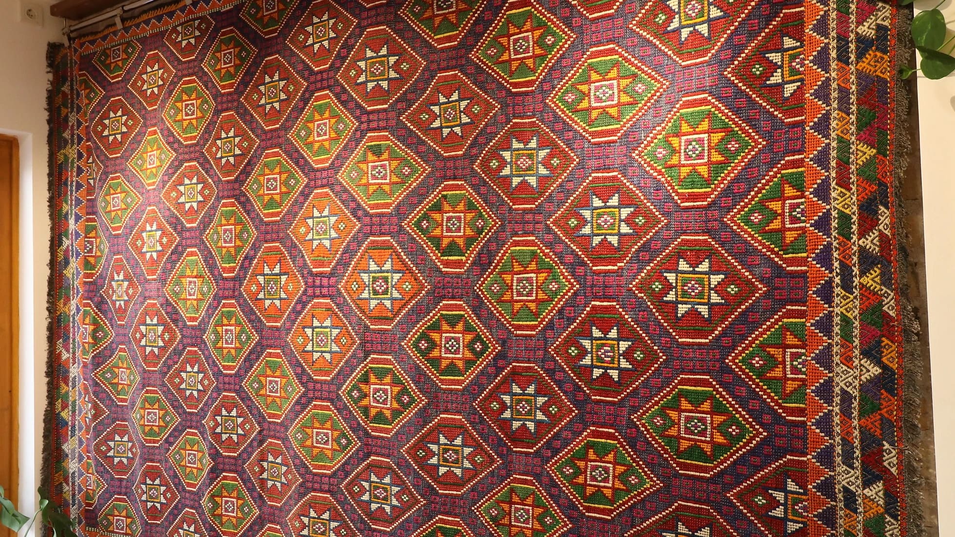 a gorgeous handwoven Turkish flat-woven tribal rug in muted and faded colors hanging on the wall as a Turkish tapestry