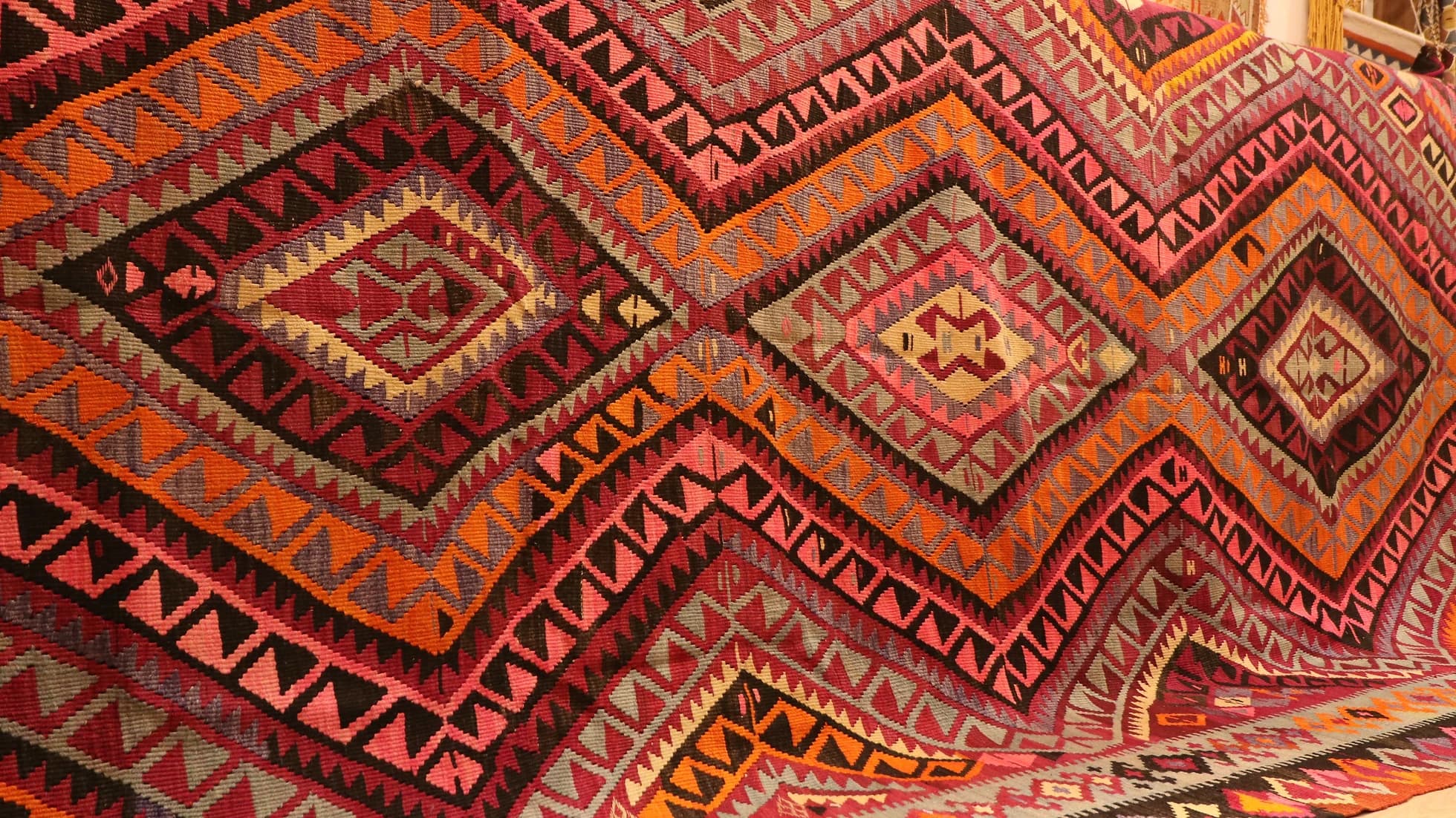 vintage handwoven flat-weave room-sized wool rug in pastel pink, red, gray, and black with diamond patterns by Kilim Couture New York