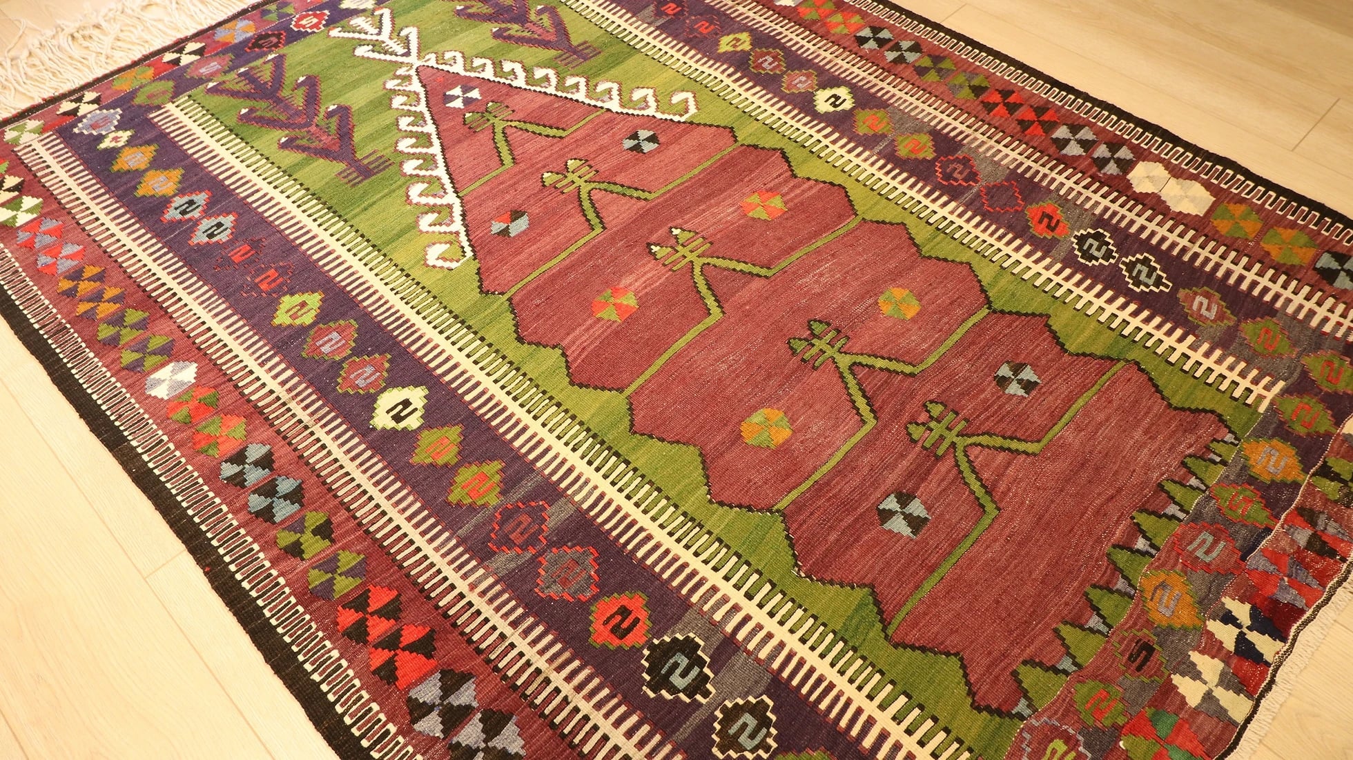 medium-sized handwoven Konya prayer rug with long white fringes featuring many traditional motifs and rustic colors