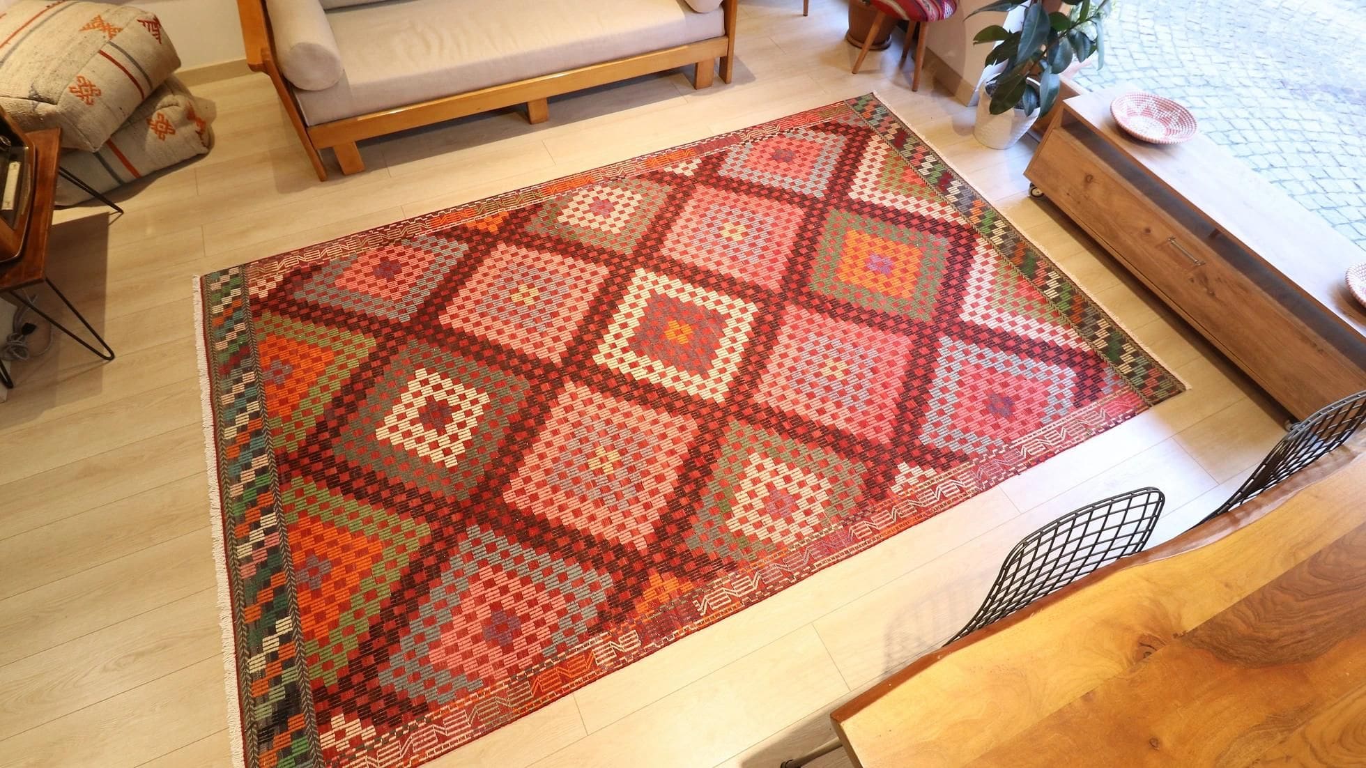 vintage handwoven Turkish wool rug in pastel pink, green, orange, blue, and purple tribal diamond patterns