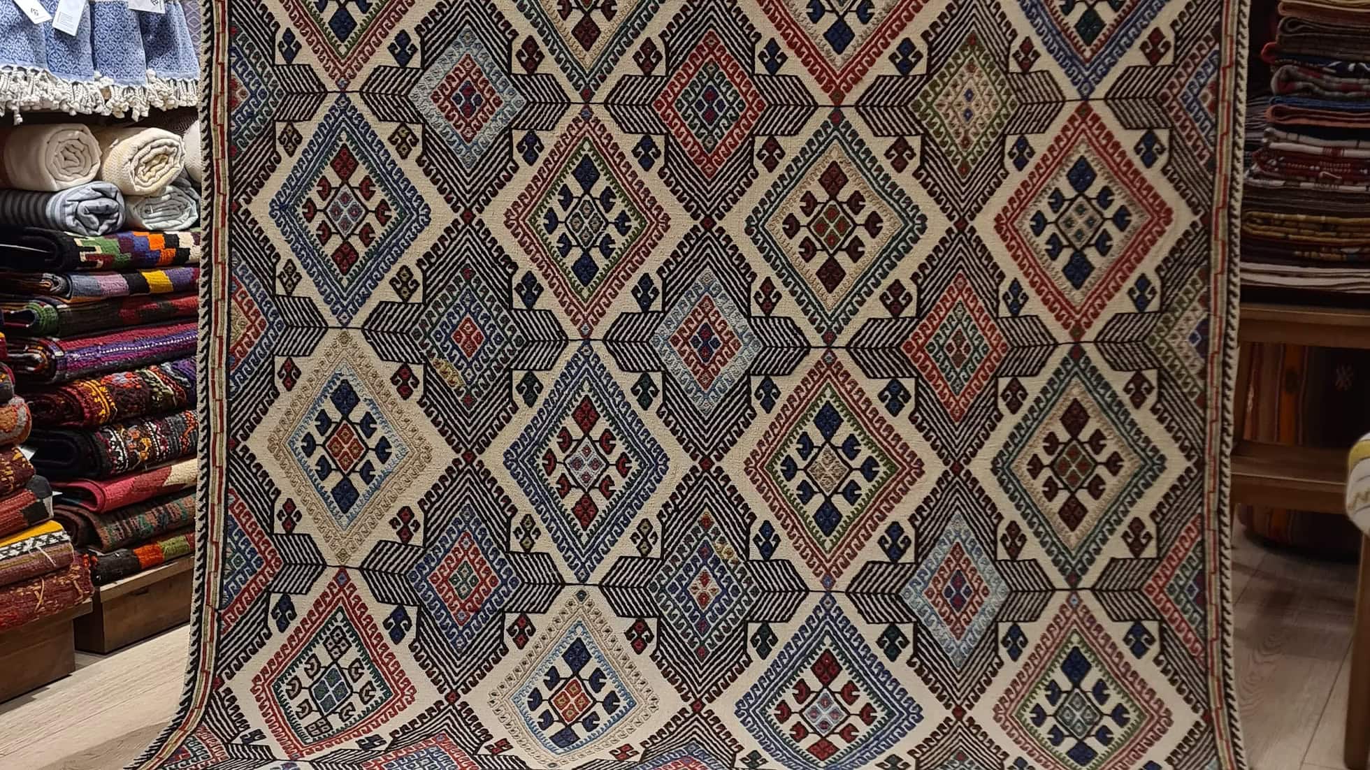Mid-Century Anatolian kilim rug with geometric diamond motifs and natural wool fibers, featuring a subtle cream field and ancient Anatolian symbols.