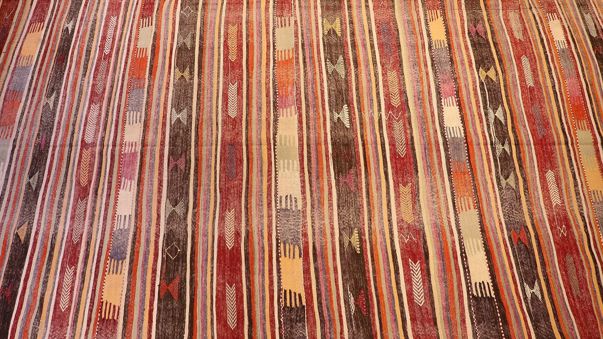 an expansive traditional kilim runner rug in pastel and rustic earth tones with geometric stripe motifs