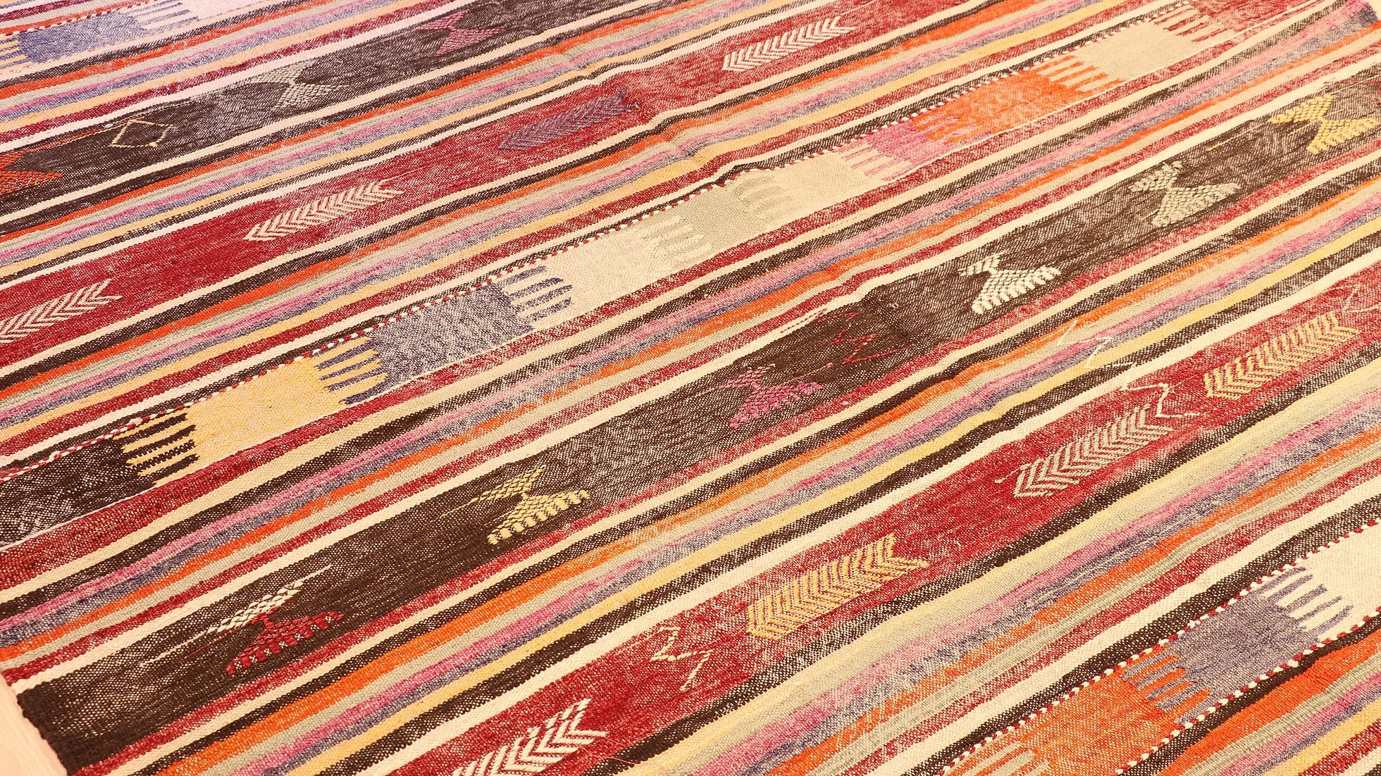 an expansive traditional kilim runner rug in pastel and rustic earth tones with geometric stripe motifs