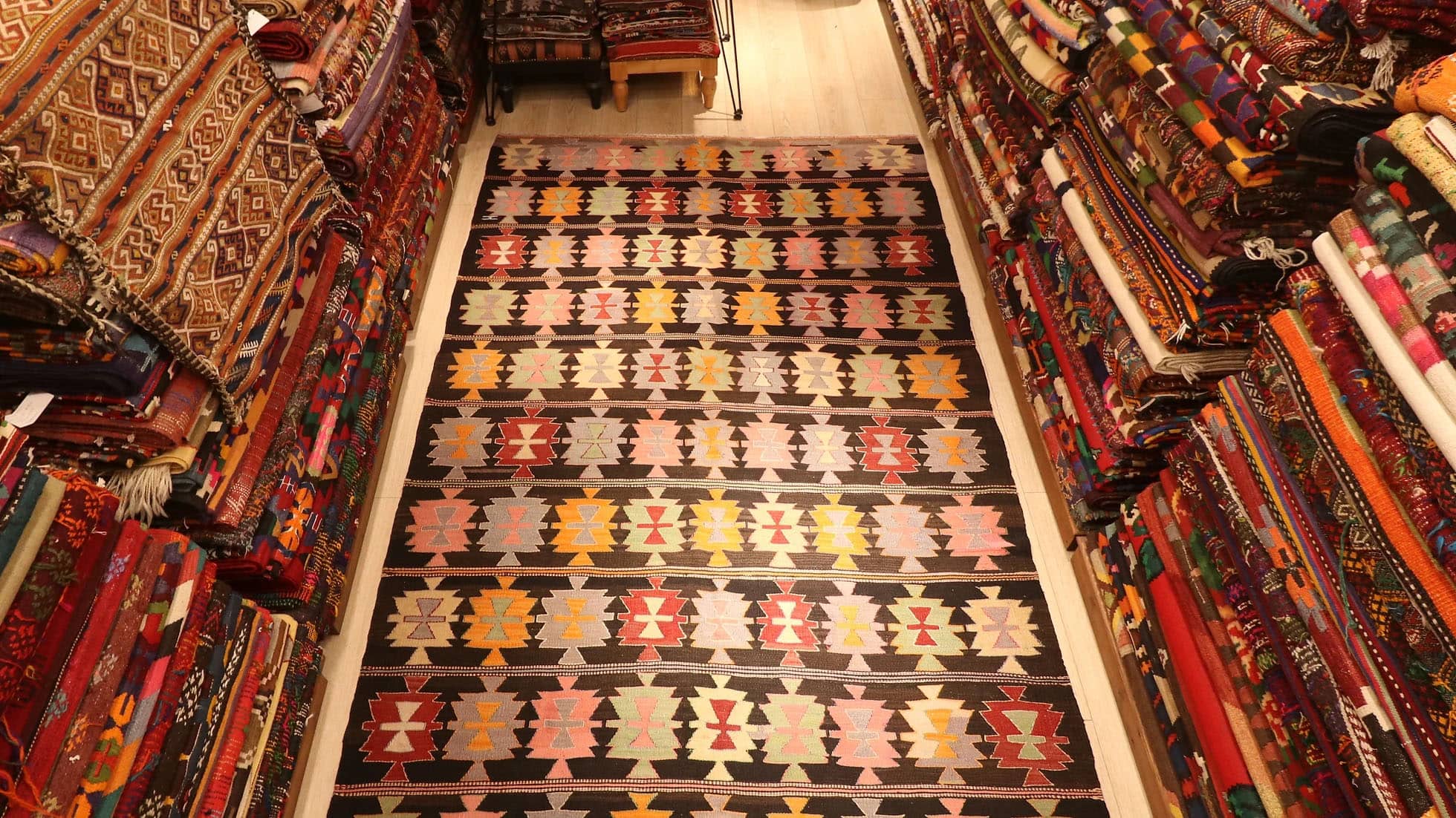 Mid-Century Maximalist Cecim Kilim, 6x10 ft, handwoven in 1940s Turkey with intricate 'hair band' motifs and bold 'fetter' patterns. Featuring a dramatic black background, it adds vibrant, layered depth to curated interiors.