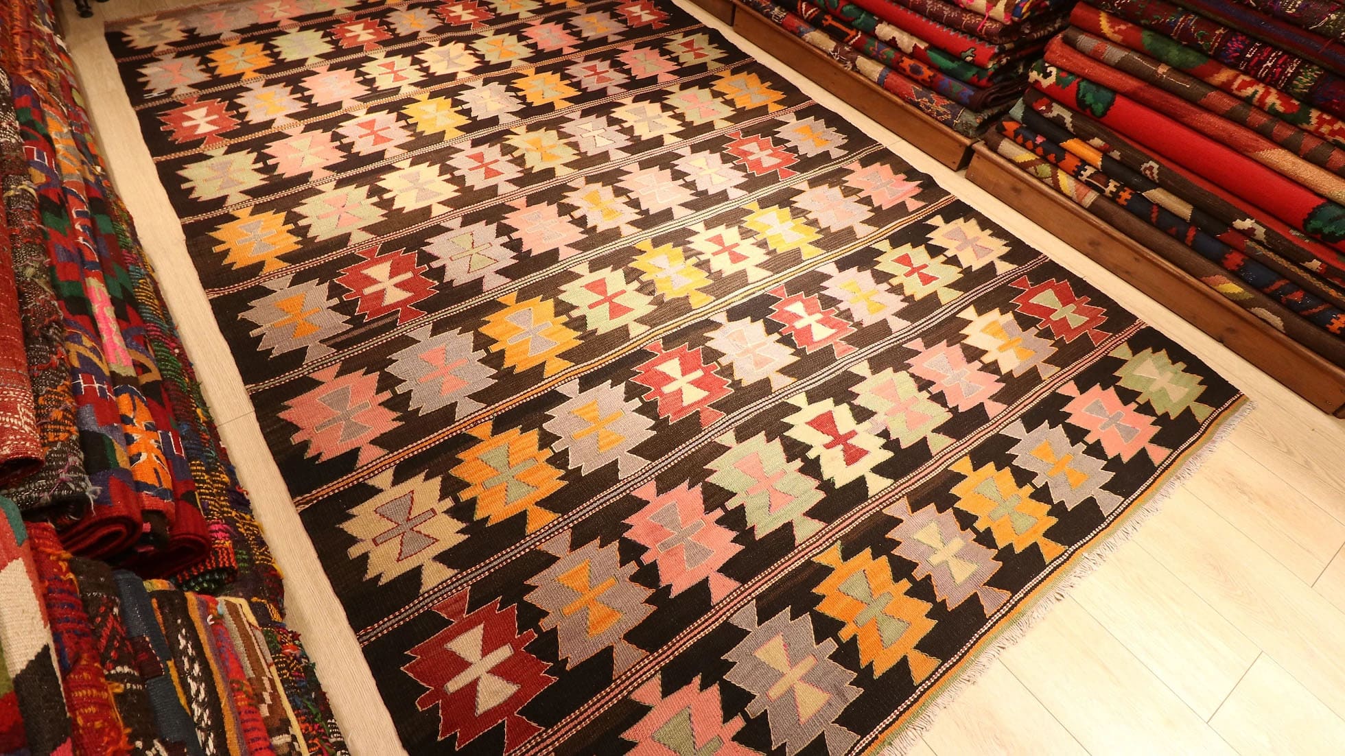 Mid-Century Maximalist Cecim Kilim, 6x10 ft, handwoven in 1940s Turkey with intricate 'hair band' motifs and bold 'fetter' patterns. Featuring a dramatic black background, it adds vibrant, layered depth to curated interiors.