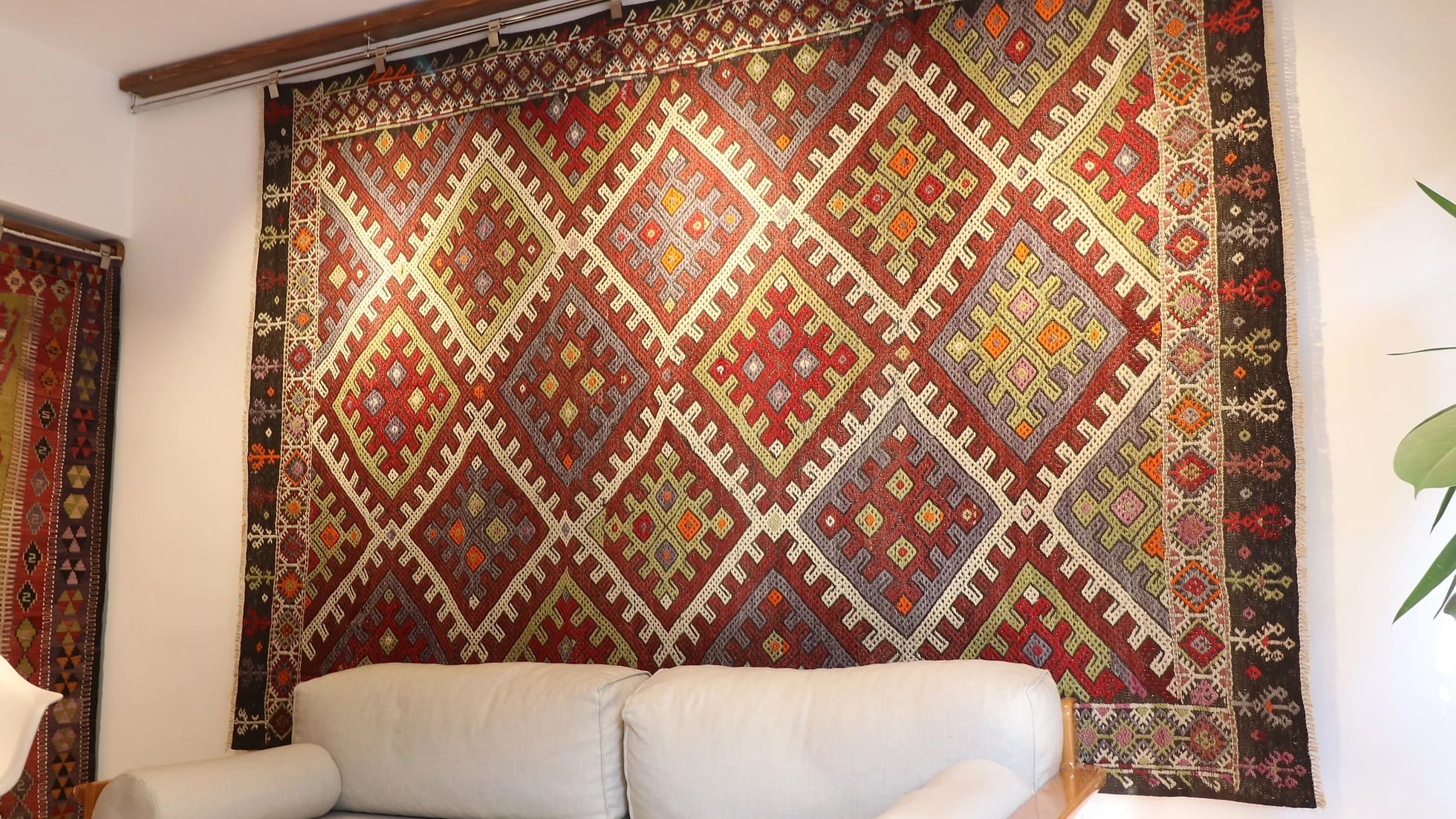 a gorgeous Turkish tribal rug featuring very rare and unseen traditional motifs in rustic and muted earth tones hanging on the wall as a Turkish tapestry from 1940s