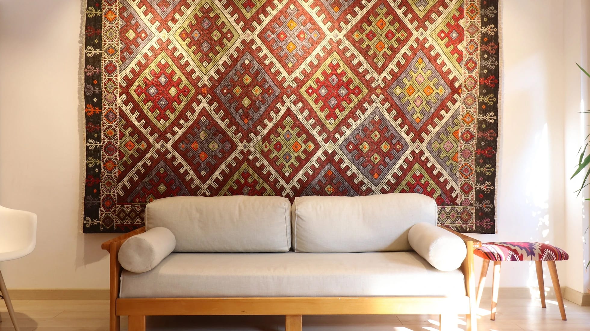 a gorgeous Turkish tribal rug featuring very rare and unseen traditional motifs in rustic and muted earth tones hanging on the wall as a Turkish tapestry from 1940s