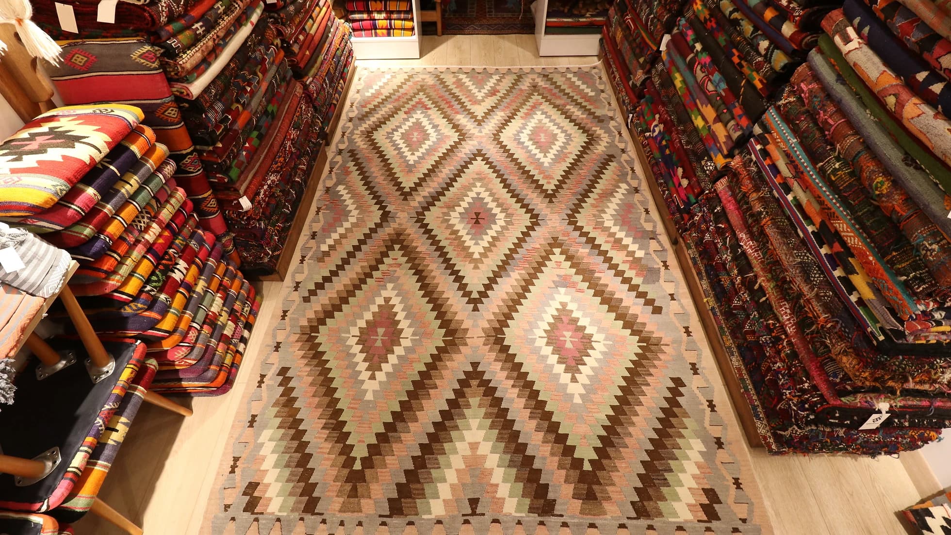 a rare large area rug from western Anatolia in pastel and neutral muted tones and diamond/lozenge patterns in our New York rug store