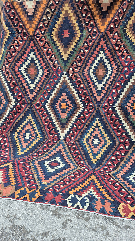 Close-up of a diamond patterned Turkish rug with geometric design in red, blue, and beige.
