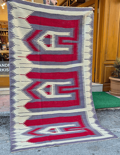 Vintage Turkish Usak rug featuring muted almond dust background and intricate comb motifs in stone gray and pomegranate.