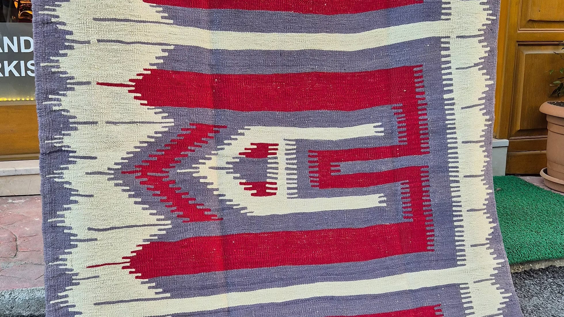 Close-up of the handwoven texture and natural dyes of a 1970s Anatolian Oushak kilim with comb motif pattern.