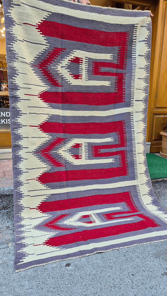 Vintage Turkish Usak rug featuring muted almond dust background and intricate comb motifs in stone gray and pomegranate.