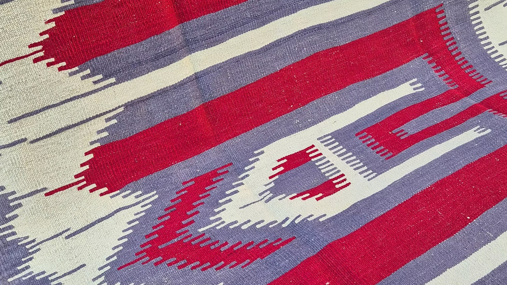 Minimalist Oushak Esme kilim displayed in a contemporary loft entrance with soft gray and warm pomegranate tones.