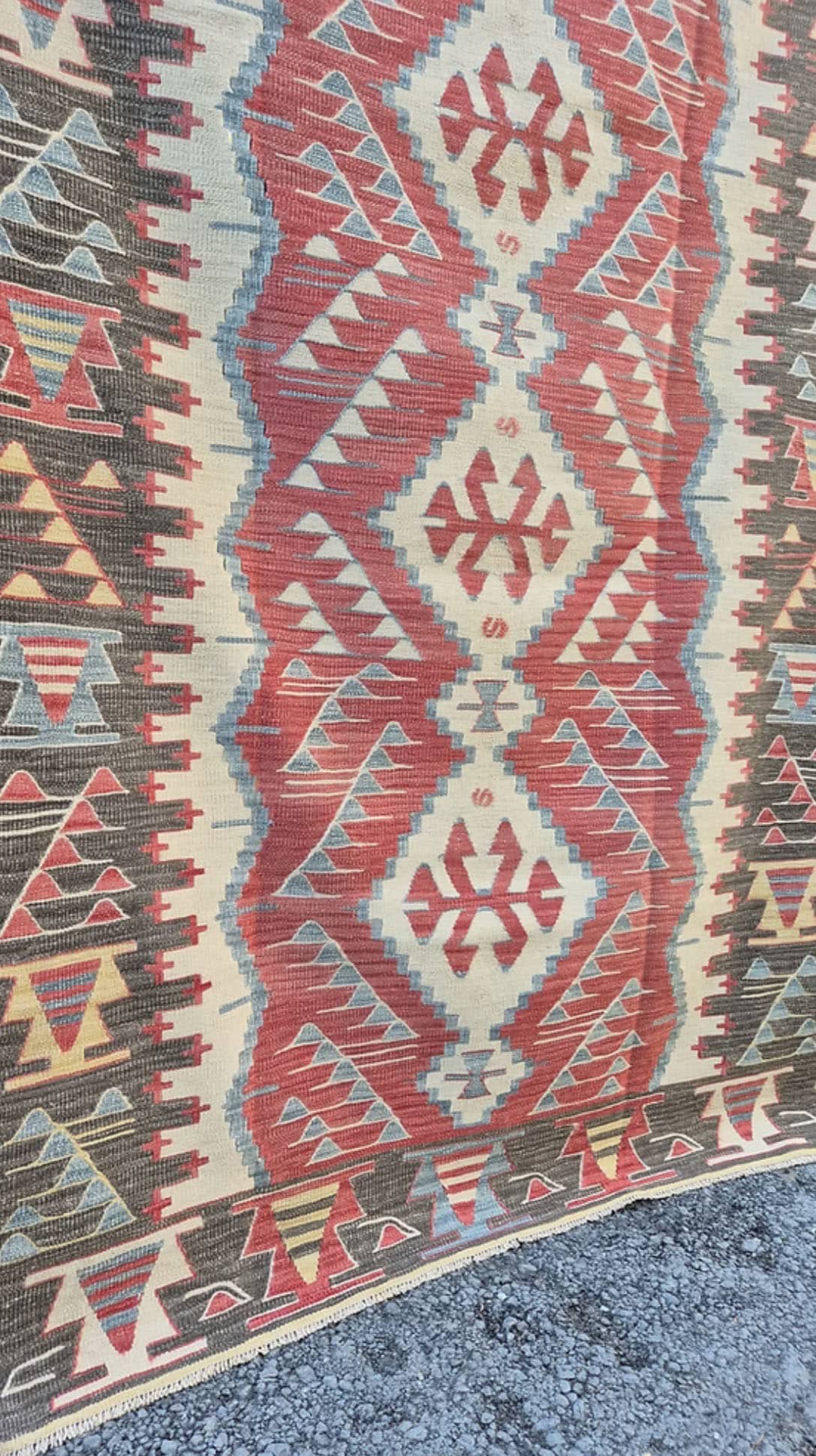 Close-up of a rustic patterned rug with geometric designs in red, beige, and blue by Kilim Couture New York Rug Gallery.