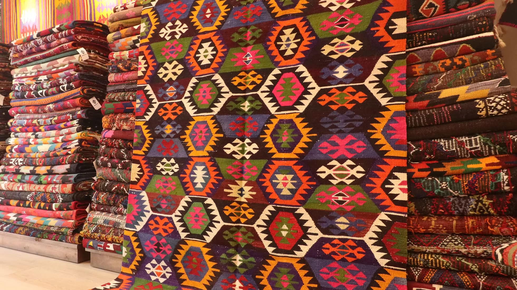 Authentic Turkish kilim from Tavas, Denizli, showcasing rich artisan craftsmanship. Vibrant hues of orchid fuchsia, marigold, and terracotta red, with intricate lozenge motifs and delicate tassels. A 5x7 ft piece that blends heritage and elegance.