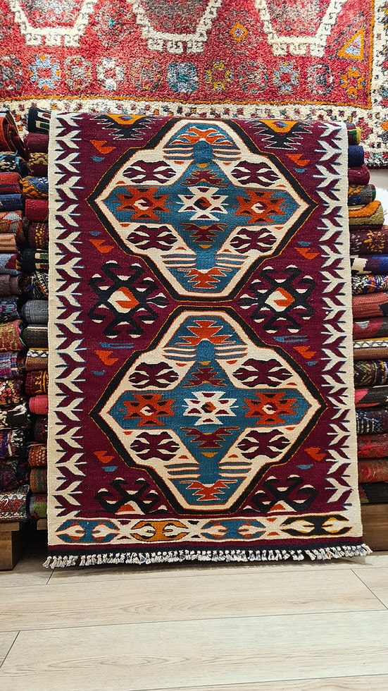 Handwoven wool kilim with deep pomegranate, terracotta, and ivory tones, adorned with 'wolf's mouth' motifs for protection, and an intricate 'elibelinde' and 'koçboynuzu' design.