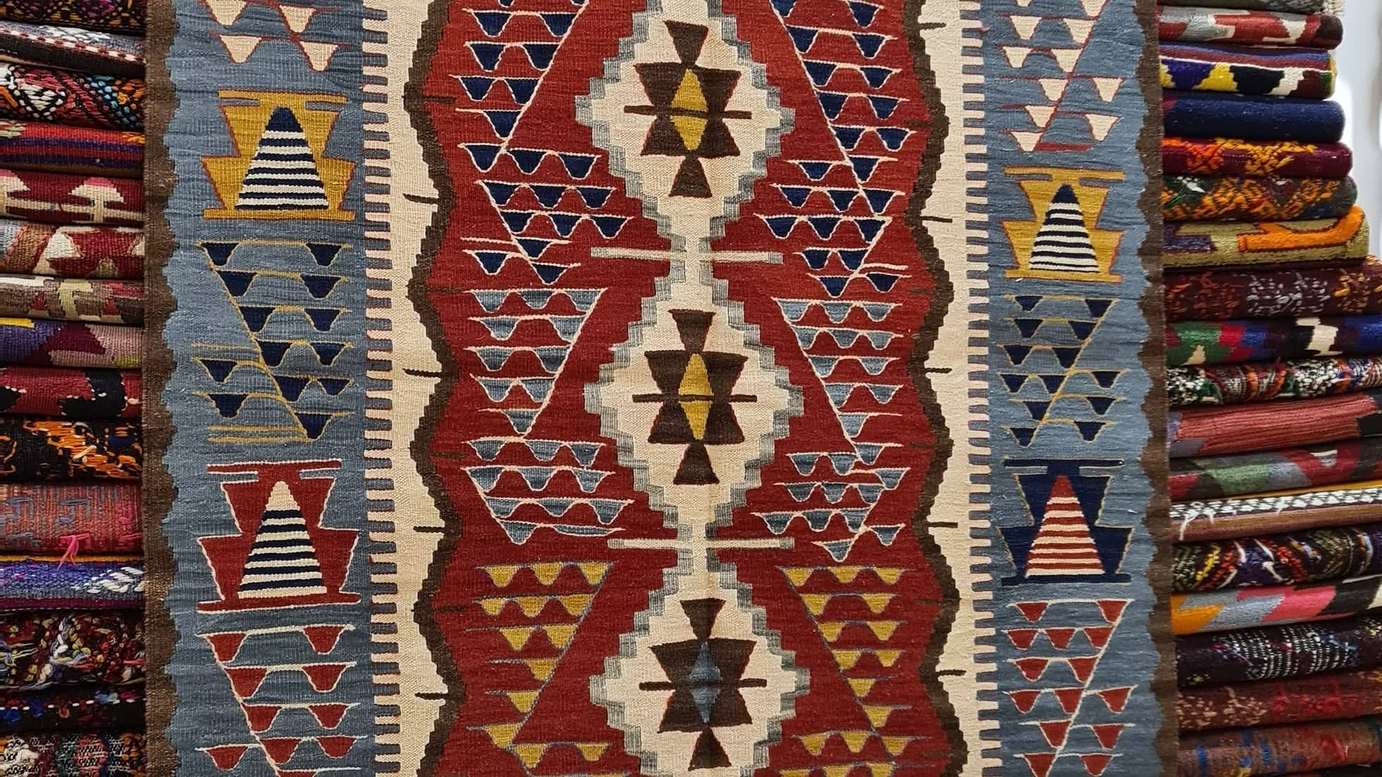 Handwoven patterned Oushak rug with geometric designs in red, ivory and blue colors.