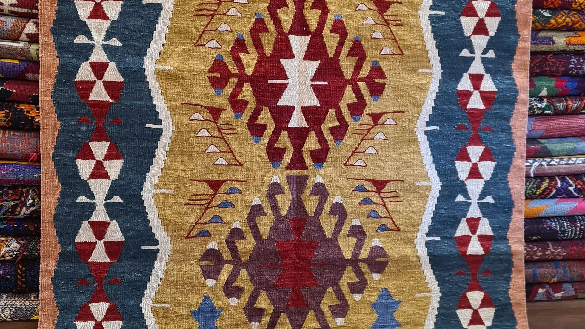 Close-up of a patterned kilim rug with geometric designs in red, blue, and gold.