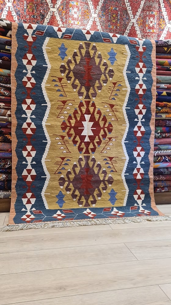 Close-up of a patterned kilim rug with geometric designs in red, blue, and gold.