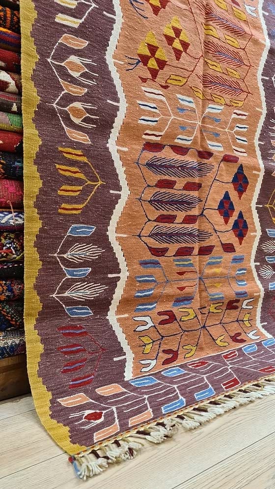 Handwoven Oushak tulip design kilim in warm saffron and walnut tones, perfect as a layered accent rug for curated spaces and modern interiors.