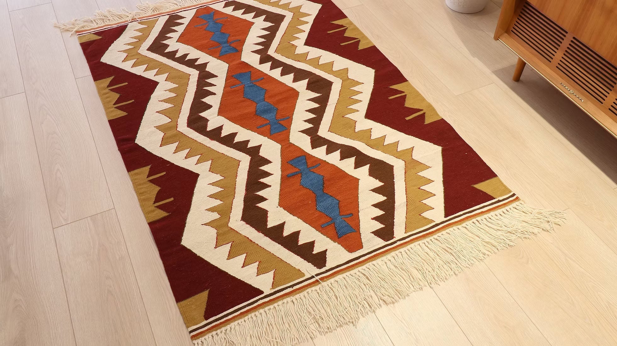 A close-up of the central inky blue diamond on a chevron kilim, which provides a calming contrast to the surrounding warm tones of amber, red, and golden hues, evoking a sense of quiet confidence and balance.