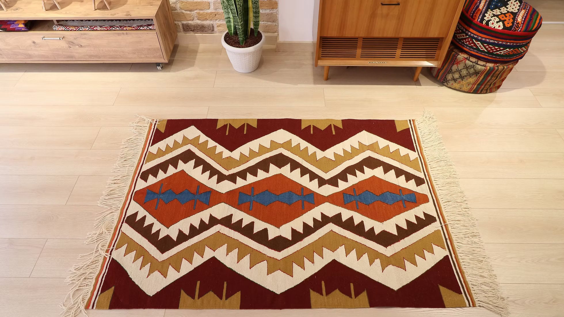 A handwoven chevron kilim from Uşak, Turkey, by Kilim Couture New York, with bold yet restrained geometric patterns in hues of toasted barley, persimmon, cinnamon, and maize, anchored by a deep blue diamond at the center.