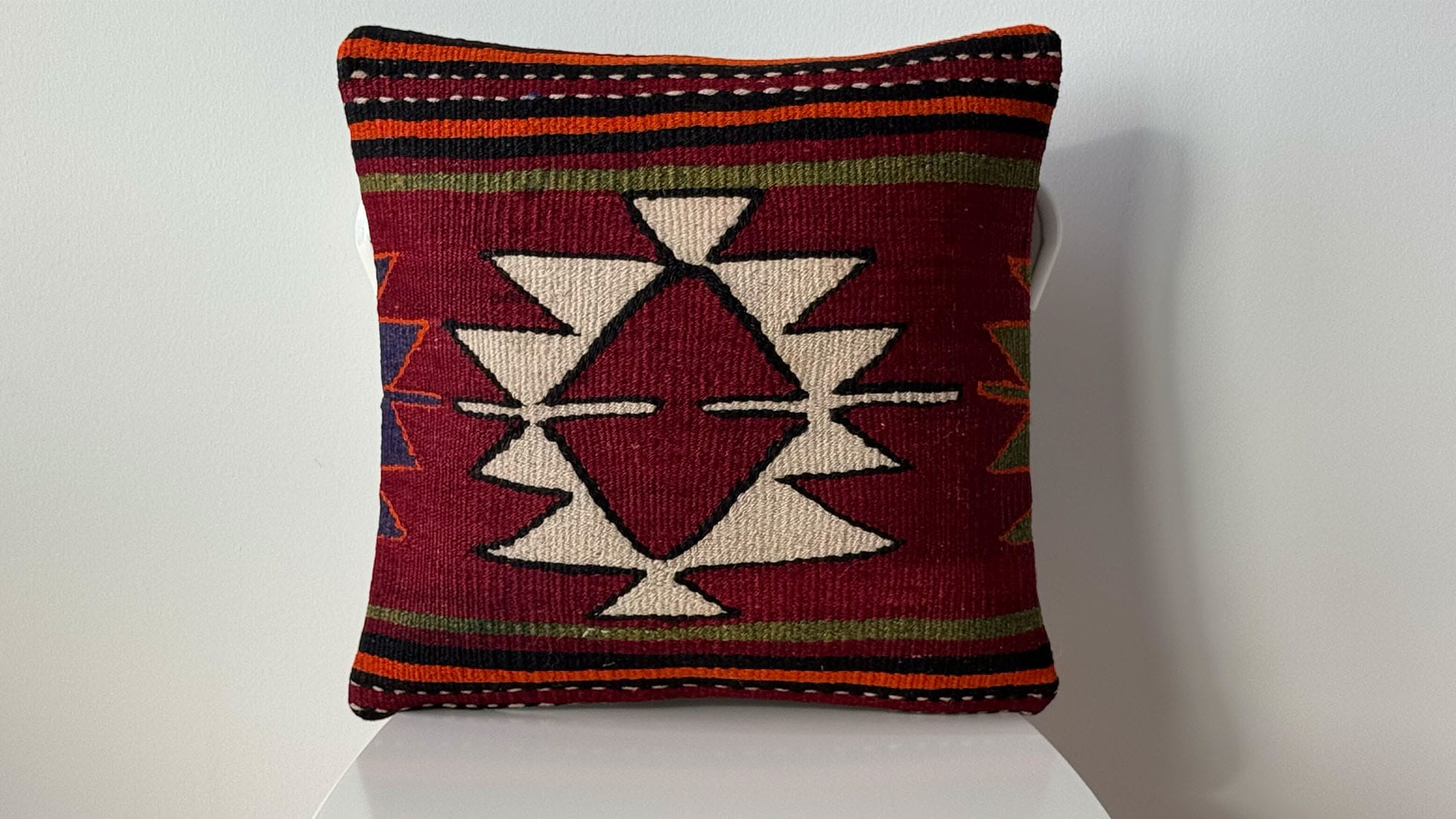 Vintage handwoven Turkish Kilim pillow with khaki, orange, and black parallel stripes, featuring a central burgundy and cream star motif, crafted by Kilim Couture New York