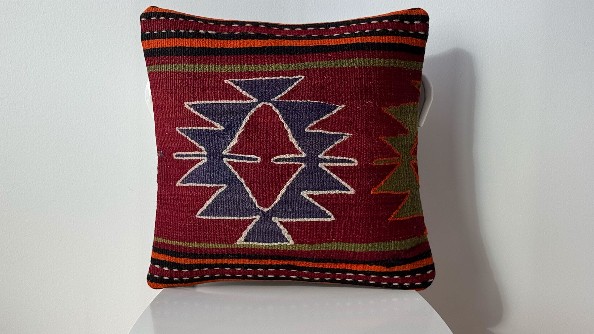 Vintage Handwoven Turkish Kilim Pillow with star motif in burgundy and blue, bordered by khaki, orange, and black stripes, crafted by Kilim Couture New York