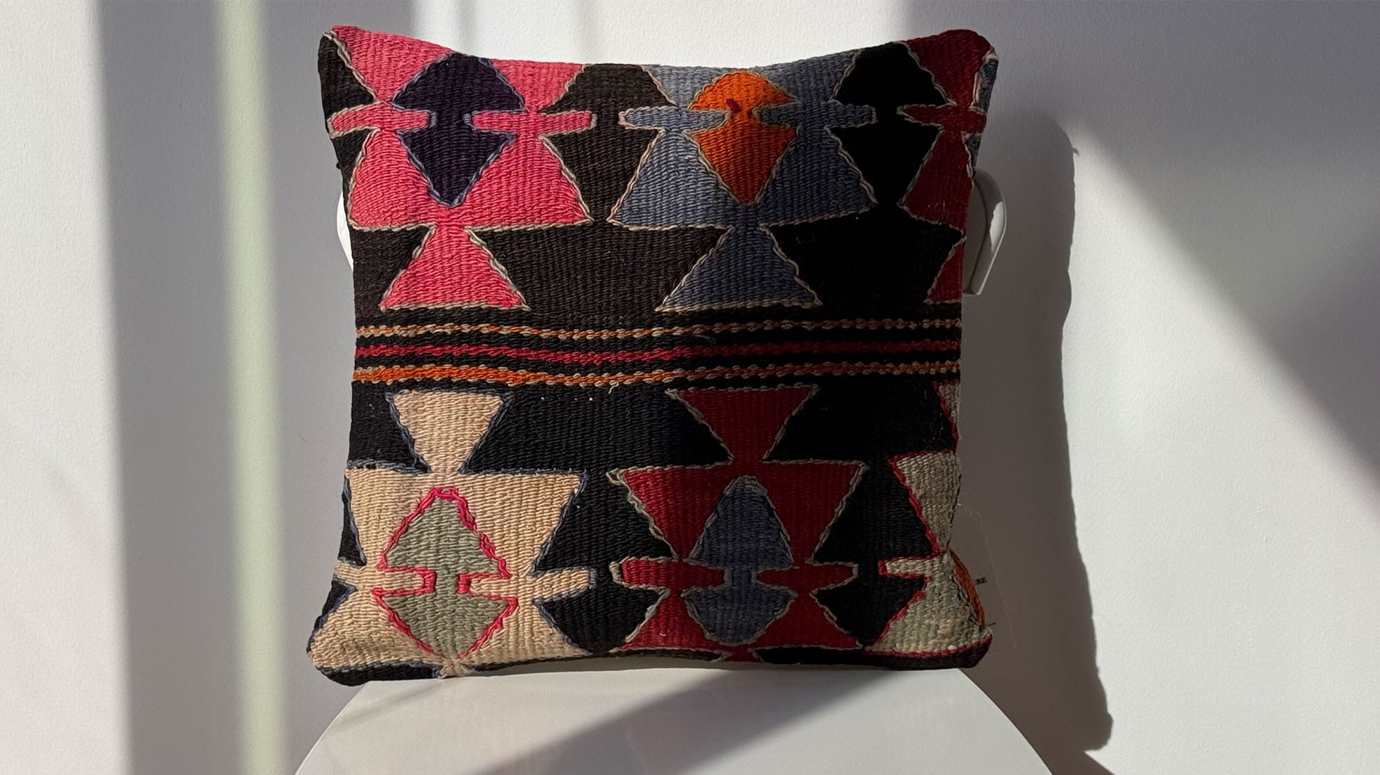 Handcrafted vintage kilim pillow in Charcoal Mist, featuring intricate 'star' motifs in red, blush pink, gray-blue, and natural cream. Made using the traditional Turkish handwoven technique, this pillow adds a touch of rustic and tribal charm to any space.