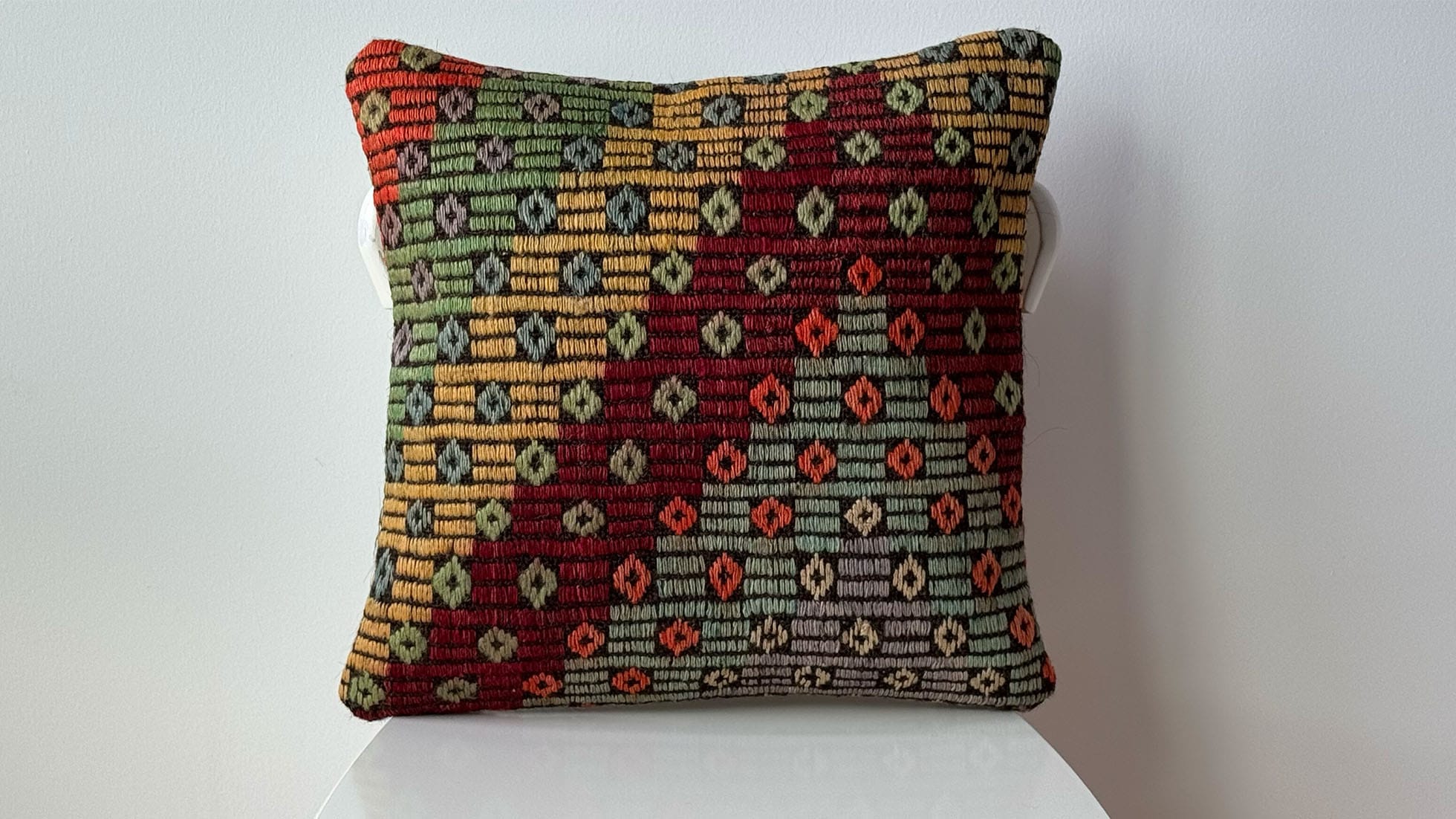 Handcrafted Vintage Kilim Pillow with rustic tribal motifs and earthy pastel tones of brick, khaki, gray, and orange. Made from premium wool and cotton, woven by Turkish women artisans using the traditional Cecim technique, perfect for elevating high-end interiors with timeless craftsmanship and sustainable luxury.