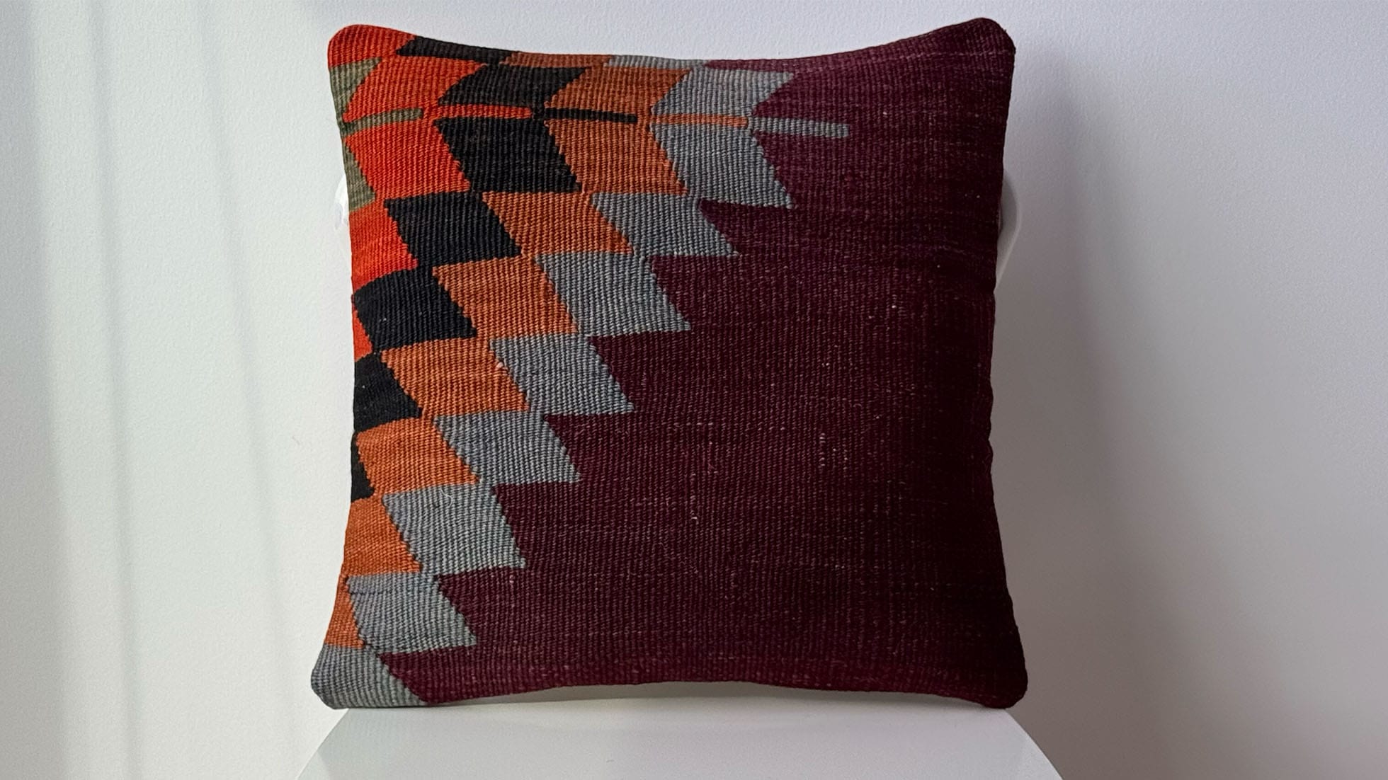 Vintage handwoven kilim pillow in plum, gray, and copper with geometric diamond patterns. Expertly crafted from a semi-antique Turkish kilim rug, this sophisticated artisanal accent adds warmth, texture, and timeless style to Western-inspired interiors, perfect for modern, rustic, and eclectic spaces.