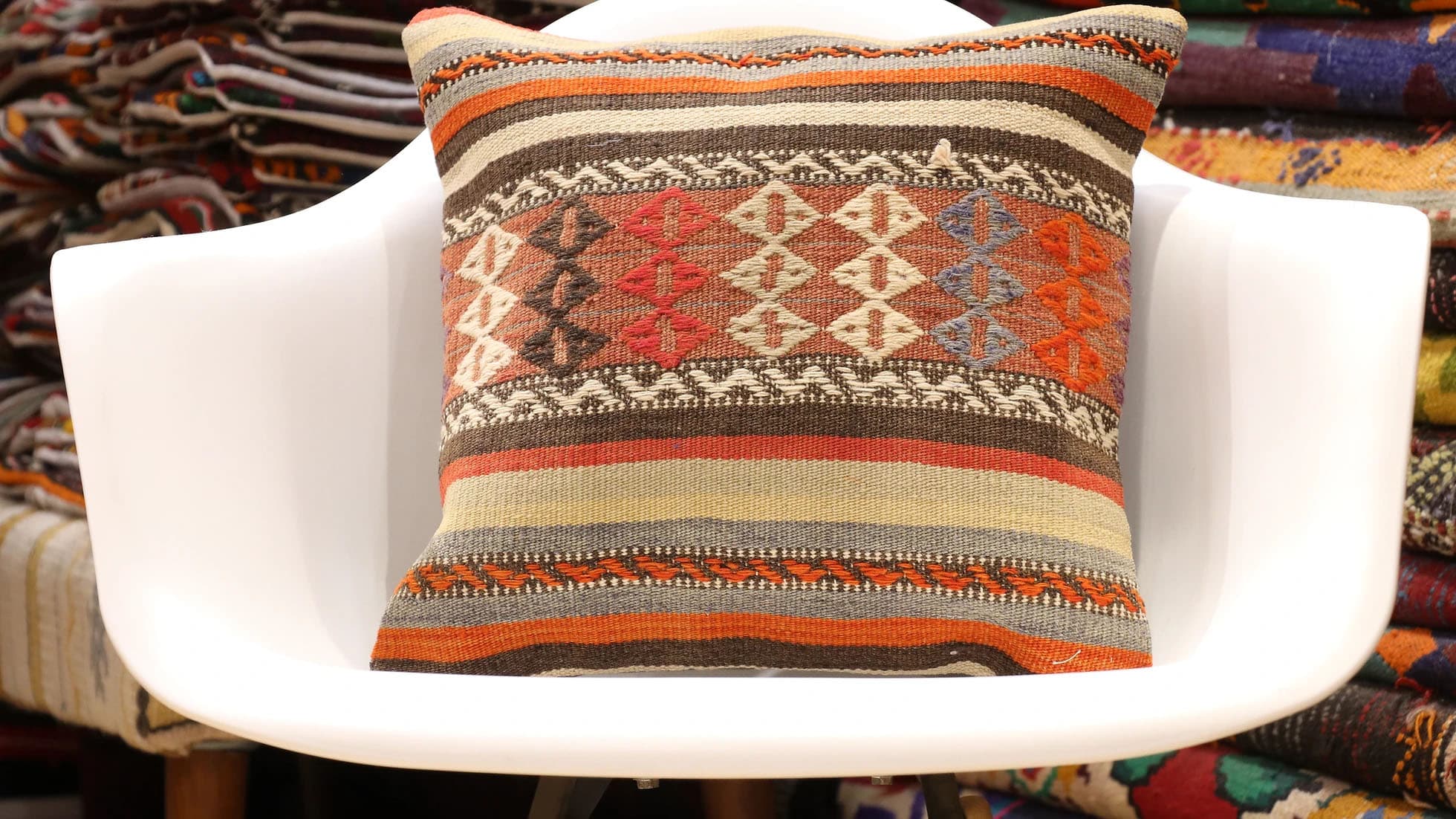 Rustic vintage handwoven Turkish kilim pillow with tribal motifs, parallel stripes, and earthy tones of rust orange, beige, gray, and taupe by Kilim Couture New York Rug Gallery